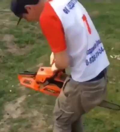 Guy trying to start a chainsaw that's pinched between his legs.