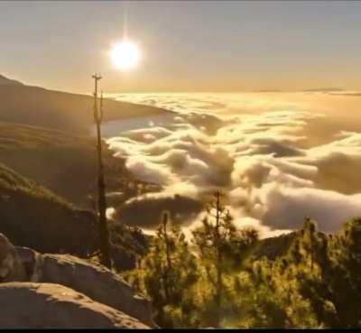 Timelapse of clouds impacting mountain look like waves on the beach