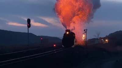 Steam train pushing full power up a gradient rains fire and ash