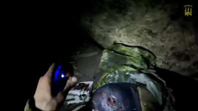 Ukranian combat medic patching up wounded comrade in a dark dugout