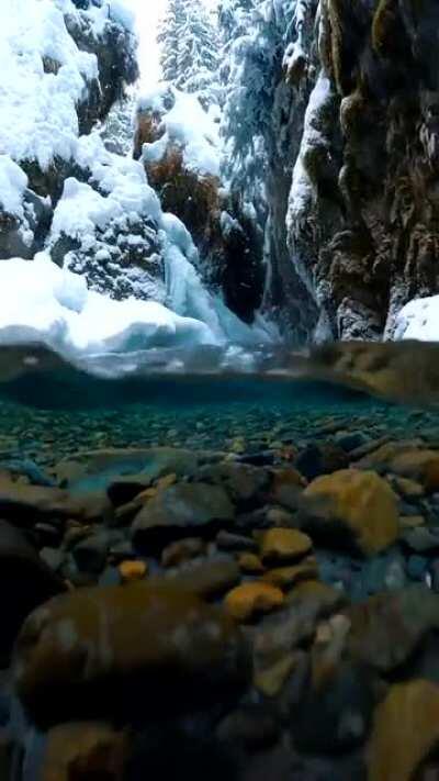 🔥 Snow falling on crystal clear Alaskan glacial meltwater captured by photographer John Derting