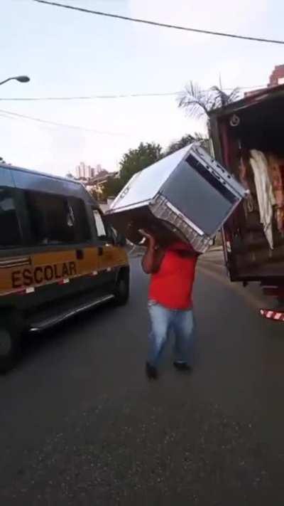 A random guy casually lifting a large refrigerator while dancing 