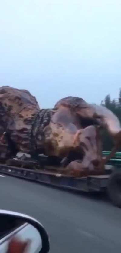 Huge carved lion being carried down the highway on a lowboy.