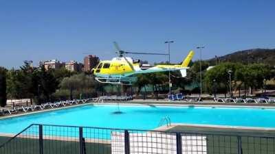 Helicopter refills its water bucket from a public swimming pool