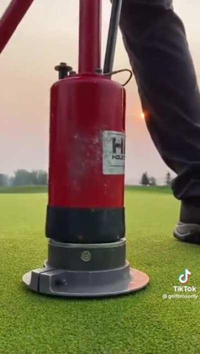 The way he fills the hole to change the pin location on a golf field.