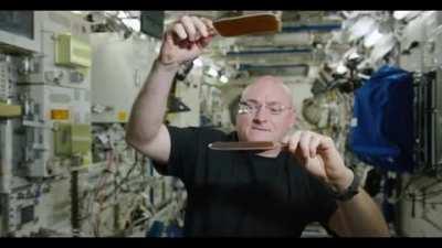 Astronaut Scott Kelly bouncing a ball of water between two hydrophobic paddles on the International Space Station