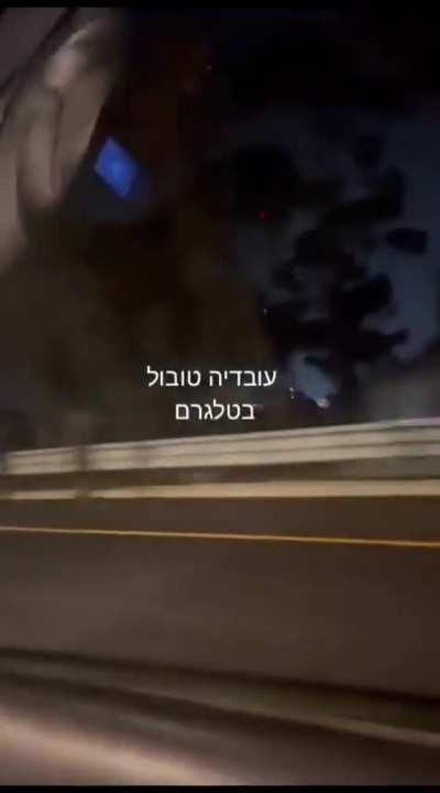 Civilian drivers passing by a firefight between Israeli police/IDF soldiers and Hamas infiltrators off the highway outside of Ashdod, Israel. 