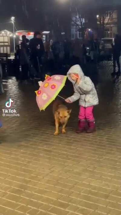 This little girl protecting the pup from the rain is the purest thing I've seen in a while