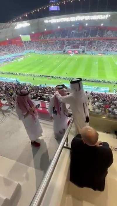 Emir of Qatars son helping an English fan with his ghutra during the England and Iran match