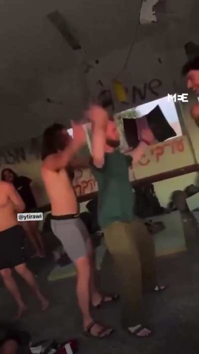 Israeli soldiers dancing in a school that was used as shelter by displaced Palestinians in Gaza, graffiti behind them reads &quot;a good Arab is a dead Arab&quot;