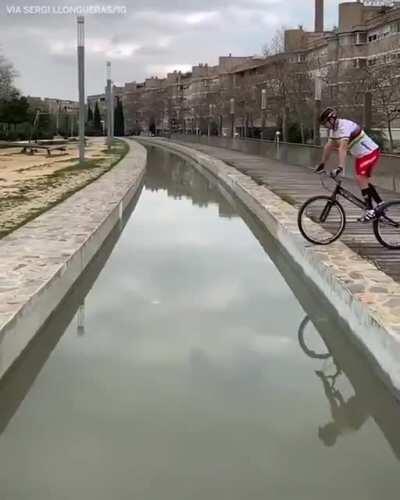 This dude jumping across a canal on his bike