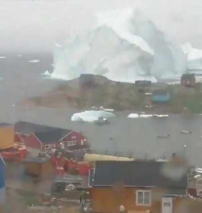 Massive Ice Berg floating past a village in Greenland