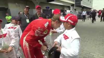 Vettel taking off a Mercedes cap on a kid, replaces it with a Ferrari cap