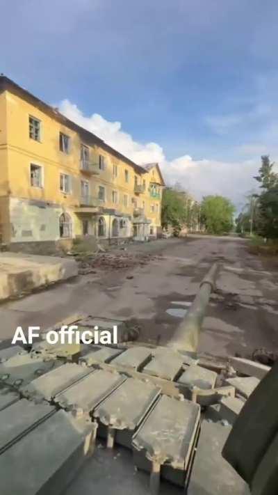 A Ukrainian tank drives through a heavily damaged town near the front.