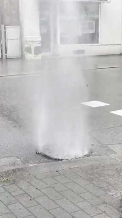 Storm in Germany. Water lifts manhole cover.