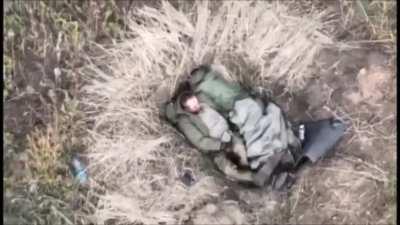 Ukrainian forces using a drone to drop a munition on two Russian servicemen who are sleeping in their foxhole.