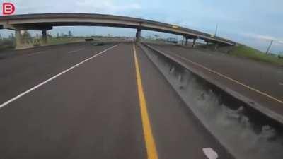 Erratic truck driver clips rider on the highway.