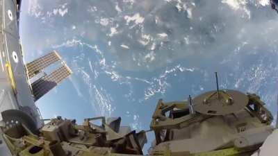 Earth in the foreground of a space walk on the ISS.