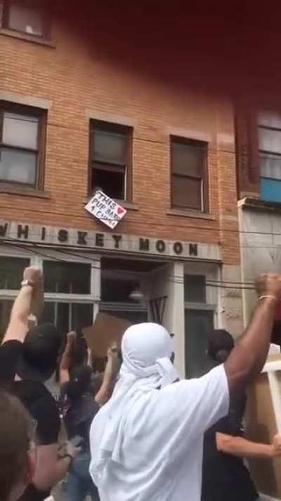 Dog showing support during a protest, the crowd loves it.