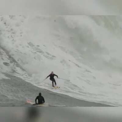 Surfer breaks out his SNOW SKIES and catches massive wave. On lookers react in disbelief.