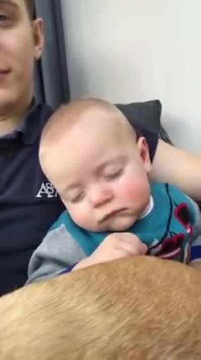 Daddy puts baby to sleep by sliding hand on his face.