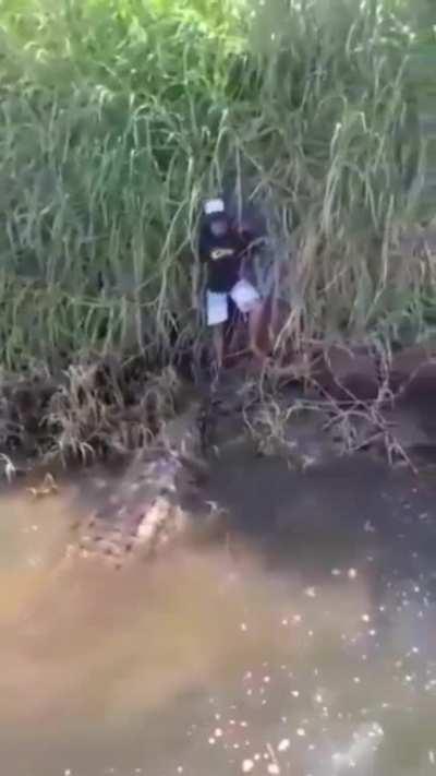 Caiman has a kid cornered and at its complete mercy. Extremely lucky the boat turned up. I would have shat my entire intestinal system out!