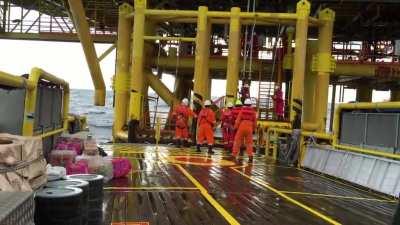 Oil workers getting onto the platform using a swing rope