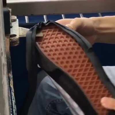 Using a hotknife to cut away excess foxing tape from a pair of Vans.