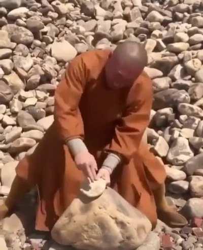 Monk brakes stones with his hands/fingers