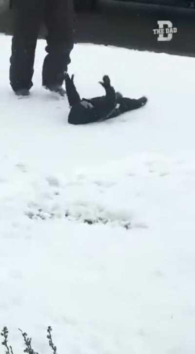 Dad teaching he’s daughter how to make a snow angel