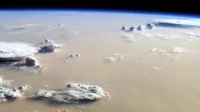 Earth looks like an alien world from the International Space Station with a massive sandstorm and towering cumulonimbus clouds covering the Sahara Desert.