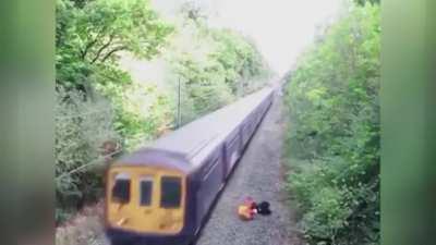 Railroad worker dives in to save a drunk cyclist as train approaches.