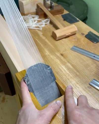 Maker of specialized blades doing a test cut of thin wood shavings