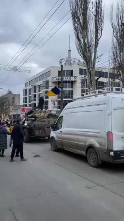 Ukrainian protester climbing on top of Russian BTR with Ukrainian flag