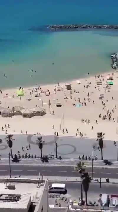 People evacuating a beach as sirens blare, indicating an incoming rocket attack (10/05/23)