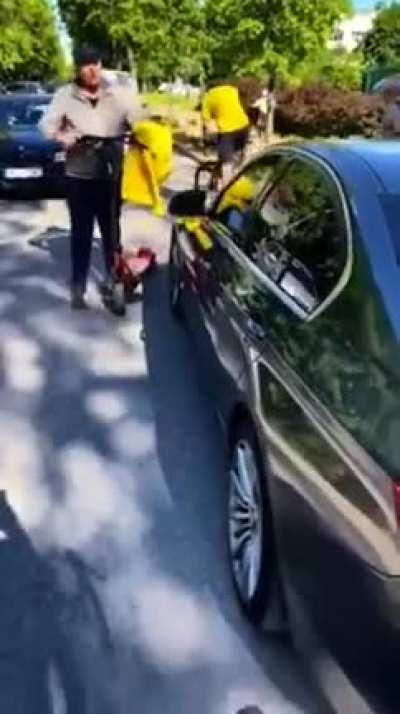 Idiot in a BMW swerves around the street cutting of cyclist on purpose, drives over an electric scooter when confronted and explodes his own tire