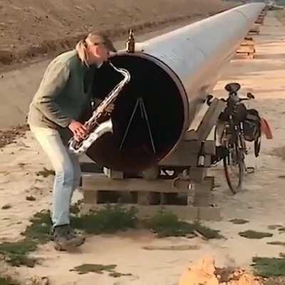 Just a man playing the sax into some pipe.