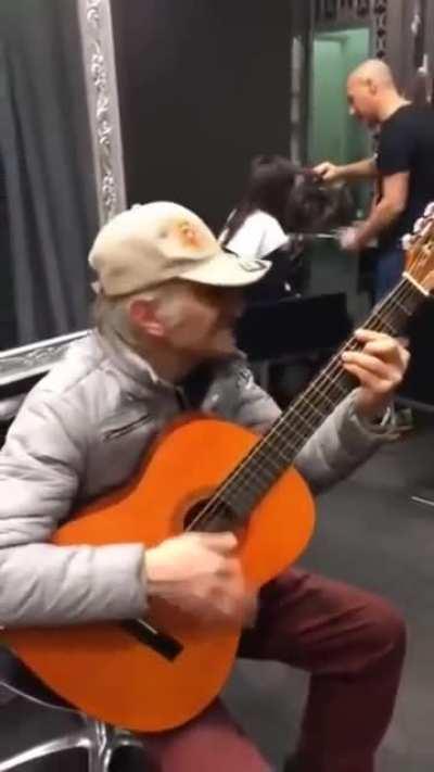 Guy in a barbershop imitates Spaghetti Western music with only a guitar and his mouth.