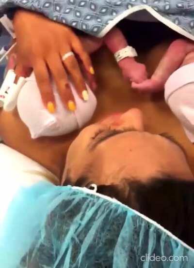 Two sisters hold hands right after birth