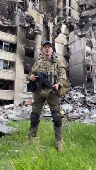 Ukrainian warrior sings Tin' Sontsya - &quot;Sword of Ares&quot; against the background of damaged buildings of the Northern Saltovka in Kharkiv. Glory to Ukraine and its soldiers.