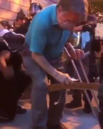 Man on crutches kneeling with peaceful protesters