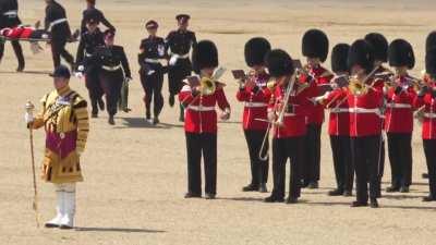 A Royal Guard trying to continue playing after fainting, while another is stretched off in the background... Hottest day of the year so far