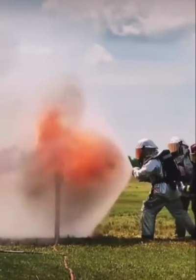 Firefighters using a water-shield to block heavy flames