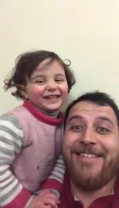 To distract his 4-year old daughter, her father has made up a game. Each time a bomb drops in Idlib Syria, they laugh, so she doesn’t get scared.