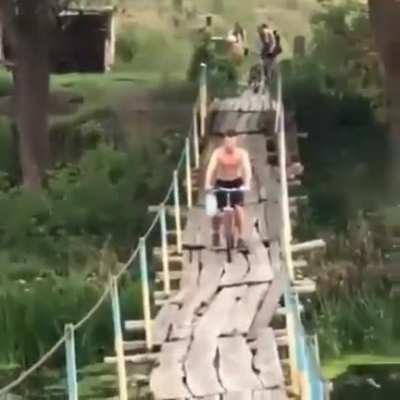 WCGW riding a bike over a rickety bridge