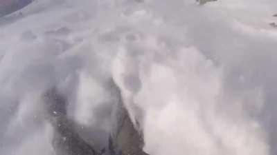 Snowboarder escapes an avalanche by riding it