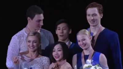 2nd and 3rd place winners of the World Figure Skating Championships help to lift the champion for podium photo