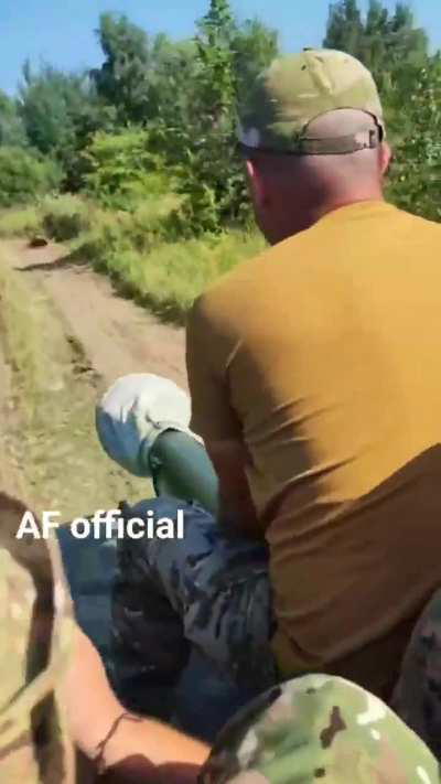 A Ukrainian crewman films as his 2S1 Gvozdika 122mm self-propelled howitzer is driven along a wooded track.