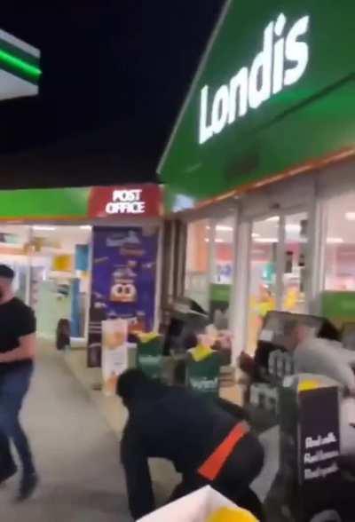 Men throw insults and a beer can at a car at a gas station in the UK