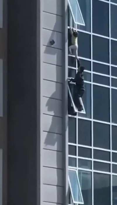 Guy climbs out of a 13th story window to save a baby that climbed out its window.